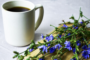 a mug with a drink and chicory flowers on a cutting board