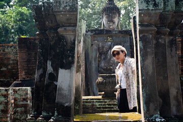 Travelers thai women people journey travel visit and shooting take photo ancient ruins of Wat Si Chum temple and Pra Ajana buddha statue in Sukhothai Historical Park in World Heritage Site at Thailand