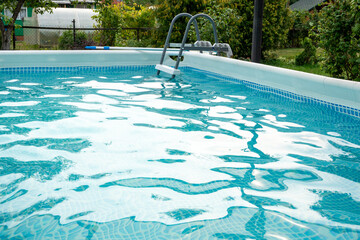 pattern of water of swimming pool with light in it and pool's stairway, a lot of space for text over blue water with play of light and shadow on pools bottom. Detail of beautiful swimming pool.