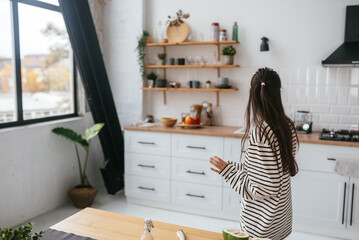 Young woman standing near desk in the kitchen