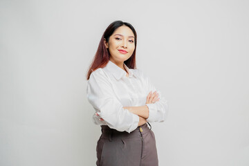 Portrait of a confident smiling Asian woman wearing white shirt standing with arms folded and looking at the camera isolated over white background