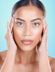 Obraz premium Portrait, face and beauty with a model black woman touching her skin in studio on a blue background. Skincare, cosmetics and antiaging with an attractive young female posing for natural treatment