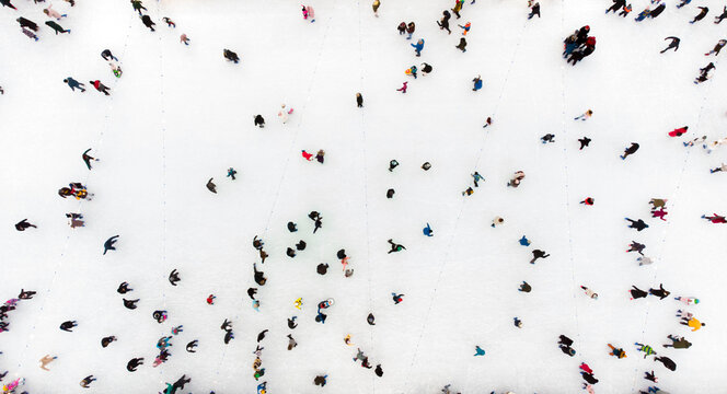 People Skating On An Open-Air Ice Skating Rink. Top View. Many People Skating On Ice Of Rink. Aerial Drone View. Beautiful Skating Sport And Winter Outdoor Activities Background