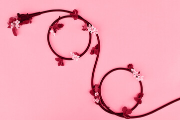 A black wire from household appliances lies on a beige background in the form of a percentage sign. Tinted image, color of the year 2023 viva magenta