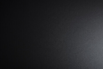 Black textured surface, side lighting. Dark empty background, top view