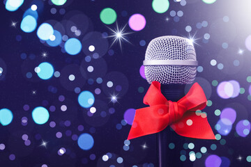 Microphone with red bow against blurred lights, space for text. Christmas music. Bokeh effect