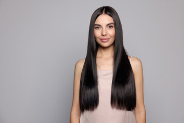 Portrait of beautiful young woman with healthy strong hair on light grey background, space for text