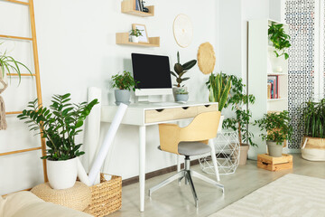 Comfortable workplace with modern computer and different houseplants in room