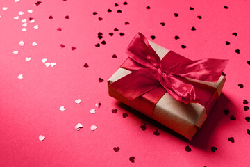 Red gift box with a ribbon for Valentines Day celebrating on Viva Magenta background with copy space