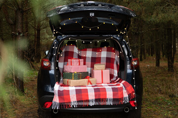 Car trunk full of gift boxes, presents and garland for Christmas holidays. forest outdoor