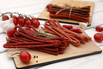 Delicious kabanosy with rosemary, peppercorn, chilli and tomatoes on white wooden table