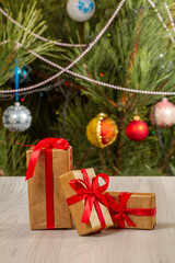Gift boxes with red bows and Christmas tree with twinkling party lights and toy balls.