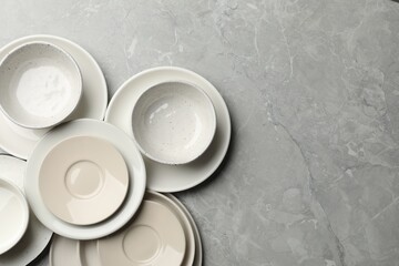 Set of clean tableware on grey table, flat lay. Space for text
