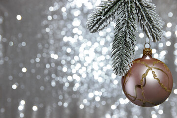 Christmas tree decoration pink ball of a snow-covered spruce branch on a blurred background of...