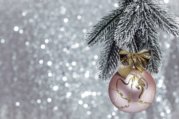Christmas tree decoration pink ball with a golden bow on a fluffy snow-covered spruce branch...
