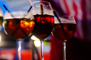 Beautiful row line of different colored alcohol cocktails on a party, martini, vodka,and others on decorated catering bouquet table on open air event, picture with beautiful bokeh