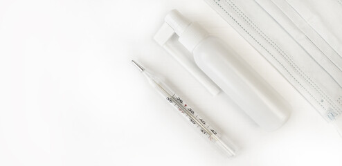 Medical glass old mercury thermometer, medical mask and throat spray on a white background....