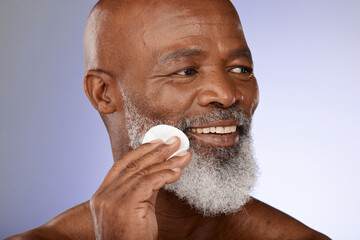 Face, skincare and antiaging with a senior black man exfoliating his skin in studio on a gray background. Beauty, cleaning and cleansing with a mature male using a cotton pad for natural treatment