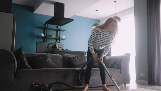 Caucasian woman has a heart attack vacuuming floor in her apartment. Adult female vacuum-cleaning the rug feels pain in her chest. Housewife cleans up the mess in the room experiences pain in heart