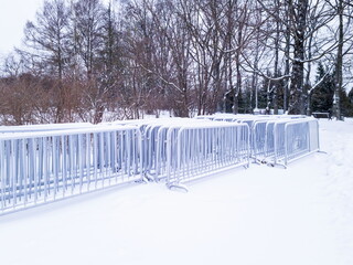 Metal fencing for mass events in winter in the park under the snow. Preparing a concert on a frosty...