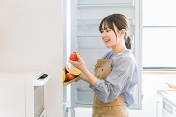 Fototapeta na wymiar 冷蔵庫からトマトを出すママ・主婦・家政婦・家事代行のアジア人女性 