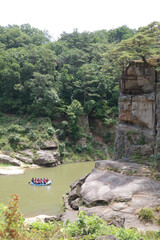 Fototapeta na wymiar A boat is operating on a river surrounded by cliffs and forests