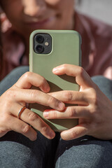 close-up detail of hands with mobile phone, behind fitness girl out of focus