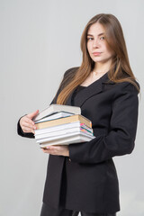 Young beautiful long-haired girl posing with books on a white background. The model is wearing a black jacket and leather pants.