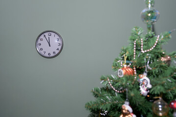 Wall clock at midnight and a decorated Christmas tree. Festive minimalism