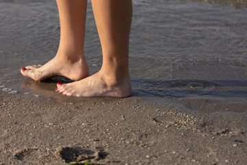 Fototapeta na wymiar Bare feet walk on the sea surf, on water and sand