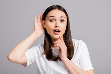 Young curious inquisitive woman girl lady standing on grey background in studio isolated holding...