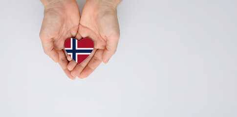 The national flag of Norway in the shape of a heart in the hands. Flat lay, copy space.