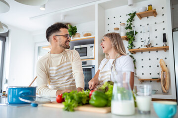 Smiling young couple cooking food in the kitchen together in the kitchen,having a great time together. Man and woman laughing