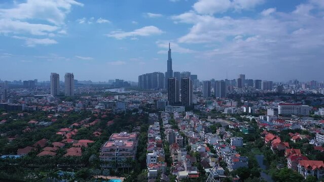 Aerial video of Ho Chi Minh City, Vietnam from Thao Dien featuring key buildings of the skyline with blue sky. Tracking R to L shot over rooftops of luxury homes.