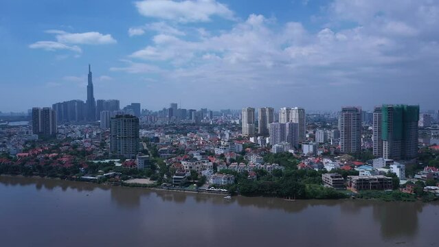 Aerial video of Ho Chi Minh City, Vietnam from Thao Dien featuring Saigon River and key buildings of the skyline with blue sky. Tracking shot R to L along river and waterfront.