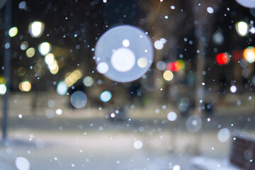 Blurred background. City view, lights, falling snow, night, street, bokeh spots of headlights of...