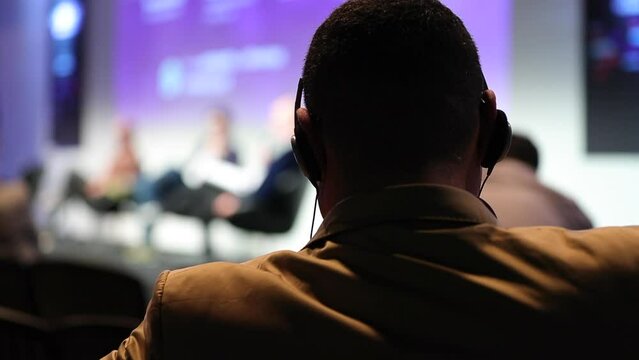 Back of people from audience perspective at conference listening to speaker