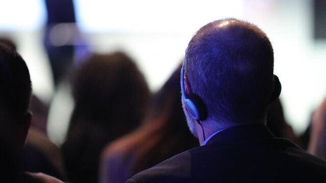 Back of people from audience perspective at conference listening to speaker