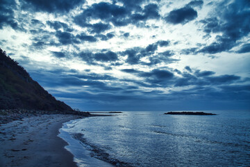 Obraz premium Sunset on the Danish coast. Beach, waves. Hill with trees in background. Landscape