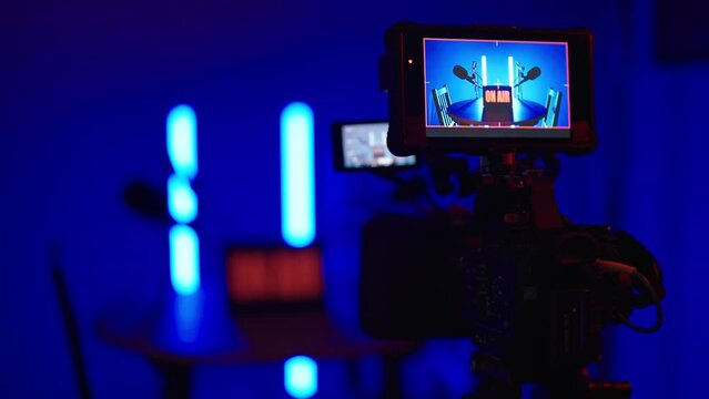 Professional camera recording dark podcast studio silhouette with neon tubes 4K