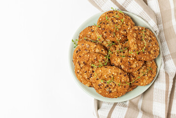 Plate whith oatmeal whole grain cookies with cereals on table napkin. Top view of biscuits with sesame, sunflower and flax seeds with copy space
