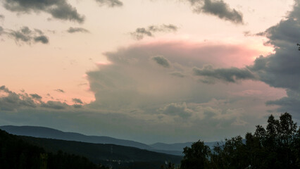Banner disturbing sunset sky with clouds and slopes overgrown with forest