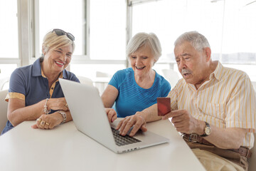 tre anziani seduti al bar fanno un ordine con il computer attraverso la carta di credito 