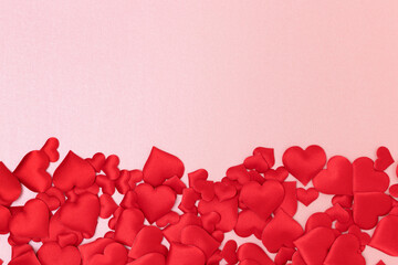 Frame made of red textile hearts confetti on a pink background. Place for text.