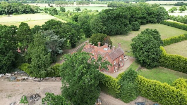 Drone rotational shot of large brick manor mansion in UK countryside farm. Taken from near Bessingham, Norwich, UK