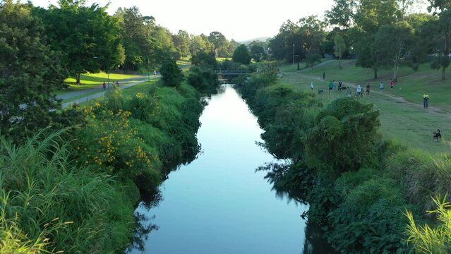 Low drone shot above creek near dog park and nature reserve. Urban lifestyle, taken at sunset. Brisbane Australia