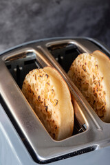 Toasted crumpets cooked in an electric toaster appliance.  On a dark stone background