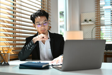 Concentrate asian male investor analyzing financial data on laptop computer