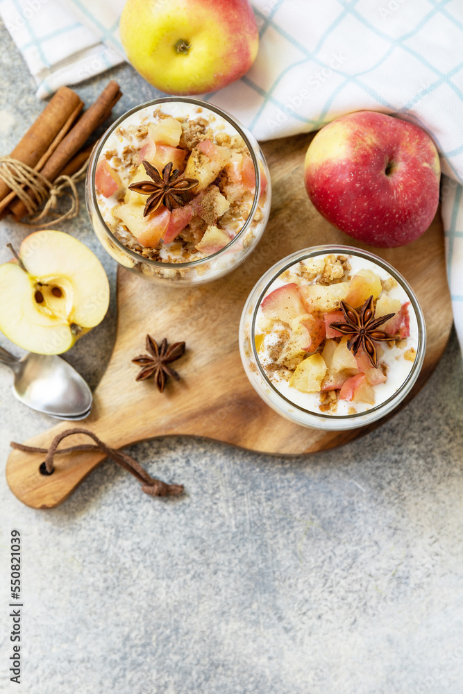 Wall mural Homemade dessert with yogurt, granola, caramel apples and cinnamon on a stone table. Healthy breakfast granola, healthy lifestyle. View from above. Copy space. - Wall murals