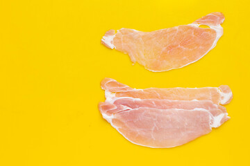 Sliced raw pork meat on yellow background.